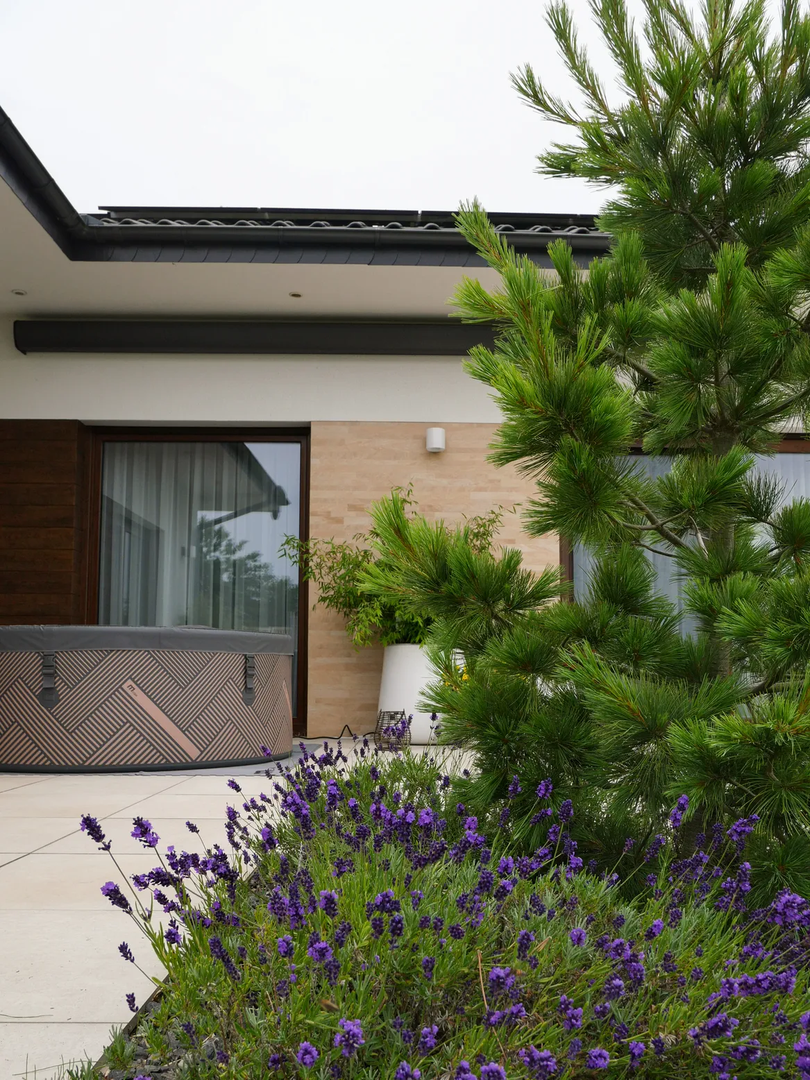 Widok na taras z sezonowym jacuzzi. W tarasie wnęka na rośliny - rabata z lawendą i sosną wejmutką