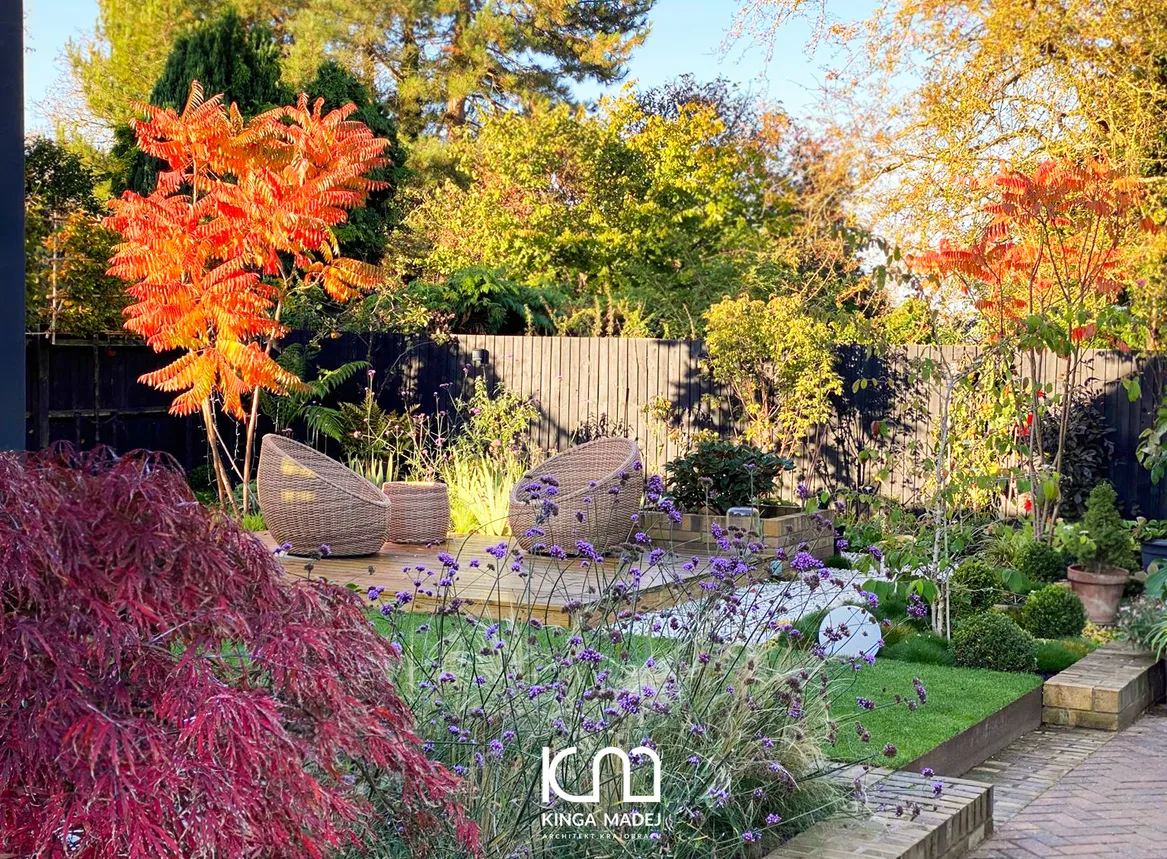 Widok na jesienną odsłonę ogrodu angielskiego. Przebarwione na pomarańczowo sumaki octowce, czerwony klon palmowy.