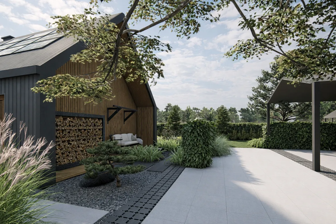 Metalowa minimalistyczna drewutnia dostawiona do ściany domu, obok huśtawka ogrodowa. Podjazd wykończony płytami wielkoformatowymi i ekokostką.