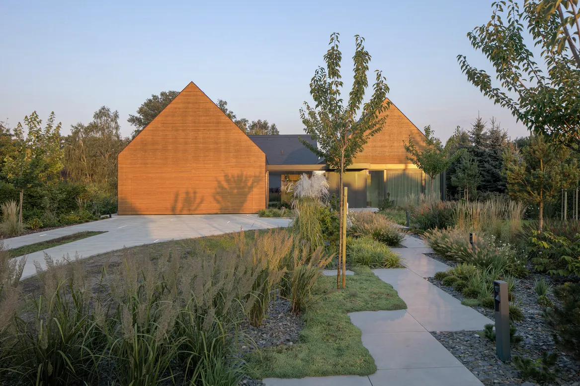 Główne wejście do domu nad rzeką. Ścieżka płyt wielkoformatowych. Rabaty ściółkowane ciemnym łupkiem. Rozplenice japońskie, rozchodnik, kosodrzewina, wiśnie Kanzan. fot. Piotr Krajewski